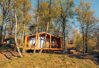 Beach Side Scandi-Lodge mit Whirlpool, umgeben von Bäumen und Natur bei strahlendem Sonnenschein.