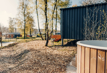Außenbereich der Beach Side Scandi Lodge in Wilsumer Berge, Deutschland, mit Badewanne und Bäumen.