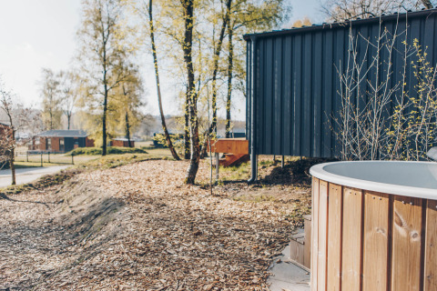 Outdoor view of Beach Side Scandi lodge at Wilsumer Berge, Germany, featuring a hot tub and trees.