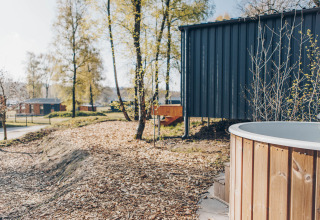 Outdoor view of Beach Side Scandi lodge at Wilsumer Berge, Germany, featuring a hot tub and trees.