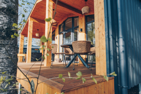 Sunny wooden terrace with rattan chairs at Beach Side Scandi lodge, Wilsumer Berge, Germany, springtime.