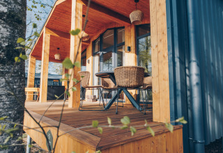 Sunny wooden terrace with rattan chairs at Beach Side Scandi lodge, Wilsumer Berge, Germany, springtime.