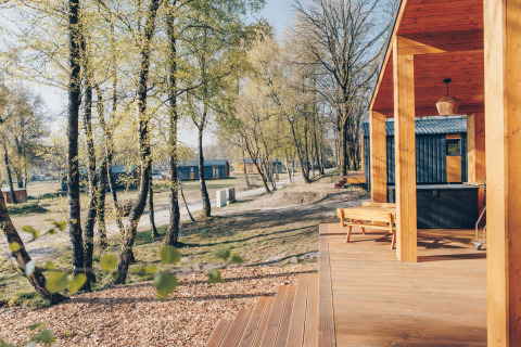 Outdoor view from the Beach Side Scandi lodge at Wilsumer Berge, Germany, with terrace and trees.