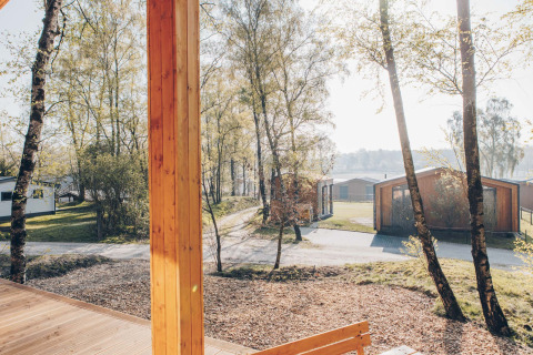 View from Beach Side Scandi lodge at Wilsumer Berge, showing trees, paths, and modern cabins in Germany.