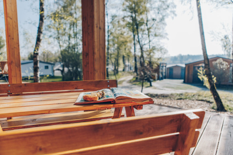 Wooden outdoor table with book and pastry at Beach Side Scandi lodge, Wilsumer Berge, Germany.