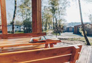 Wooden outdoor table with book and pastry at Beach Side Scandi lodge, Wilsumer Berge, Germany.