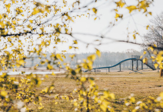 View of a playground near the beach at Beach Side Scandi, Wilsumer Berge, Germany, with yellow leaves in front.