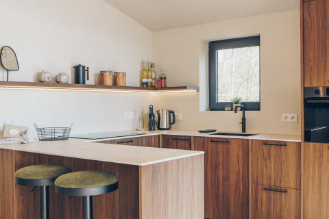 Modern kitchen at Beach Side Scandi in Wilsumer Berge, Germany featuring wood cabinets and green stools.