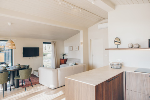 Bright Scandinavian-style Beach Side Scandi lodge interior at Wilsumer Berge, with kitchen, sofa, and dining area.