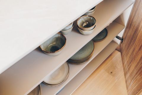 Ceramic bowls and plates neatly stored in the kitchen cupboard at Beach Side Scandi Lodge, Wilsumer Berge.
