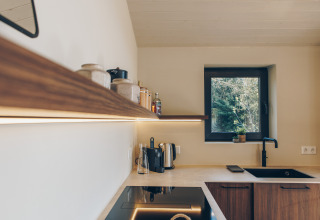 Modern Scandinavian kitchen at Beach Side Scandi lodge, Wilsumer Berge, Germany, with wooden shelving.