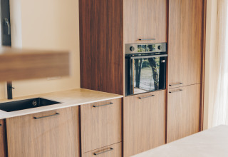 Bright modern kitchen at Beach Side Scandi lodge in Wilsumer Berge, Germany, with built-in oven and wood cabinets.