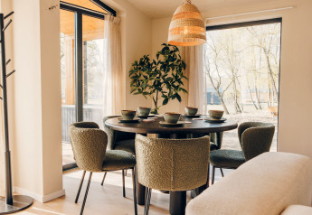 Moderner Essbereich mit grünen Stühlen und rundem Tisch am Fenster in der Beach Side Scandi-Lodge, Wilsumer Berge.