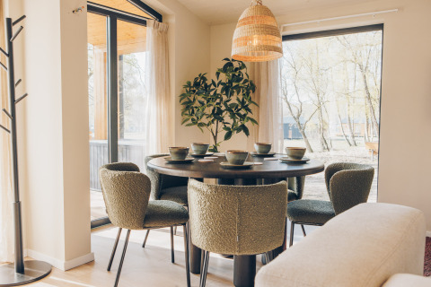 Modern dining area with green chairs and a round table by large windows at Beach Side Scandi lodge, Wilsumer Berge.