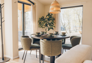 Modern dining area with green chairs and a round table by large windows at Beach Side Scandi lodge, Wilsumer Berge.