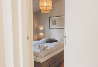 A peek into a cozy bedroom with a double bed, soft lighting, and modern Scandinavian decor style.