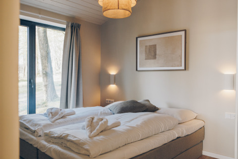 Cozy bedroom at Beach Side Scandi lodge in Wilsumer Berge, Germany, with scenic forest view outside.