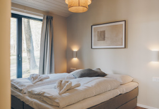 Cozy bedroom at Beach Side Scandi lodge in Wilsumer Berge, Germany, with scenic forest view outside.