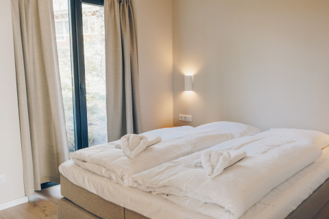 Bright bedroom with double bed, soft duvets, and window at Beach Side Scandi, Wilsumer Berge, Germany.