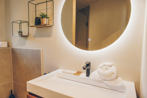 Contemporary bathroom at Beach Side Scandi, Wilsumer Berge, Germany, with round mirror and décor.