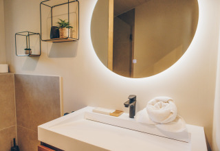 Contemporary bathroom at Beach Side Scandi, Wilsumer Berge, Germany, with round mirror and décor.