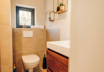 Modernes Badezimmer mit Hänge-WC, Holzschrank, kleinem Fenster und Pflanzenregalen im Beach Side Scandi.