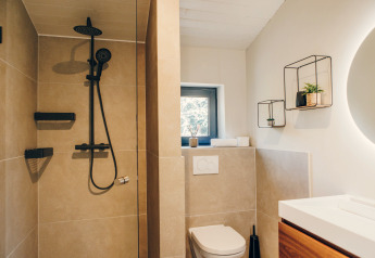 Modernes Badezimmer mit Dusche, schwarzen Armaturen und skandinavischer Deko im Beach Side Scandi-Lodge.