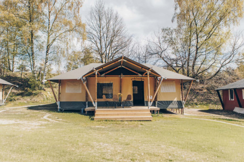 Safaritent Glamfield Lodge II bij Wilsumer Berge in Duitsland, omringd door bomen en grasveld.