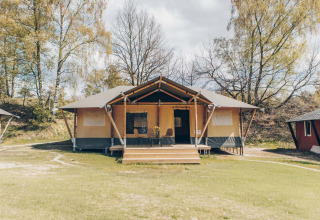 Safaritent Glamfield Lodge II bij Wilsumer Berge in Duitsland, omringd door bomen en grasveld.