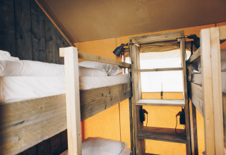 Interieur van het Glamfield Lodge safaritent met houten stapelbedden bij Wilsumer Berge in Duitsland.