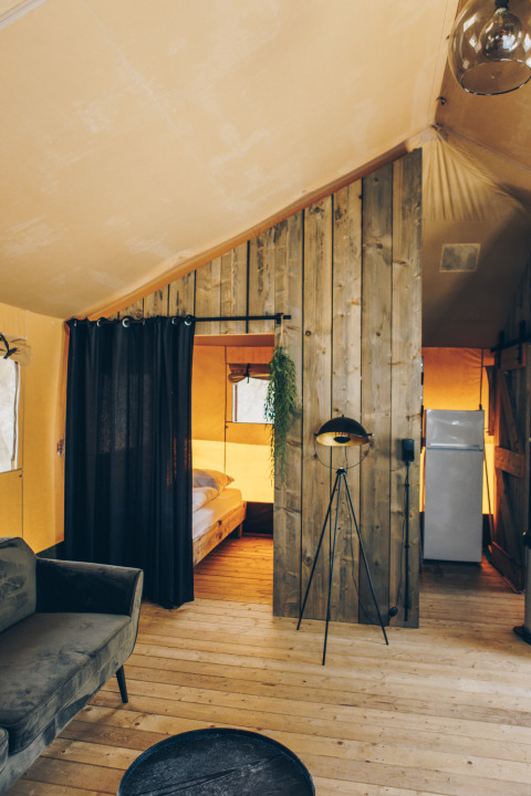 Interieur van de safari tent Glamfield Lodge op Wilsumer Berge in Duitsland met warme houten inrichting.