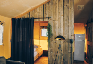Interieur van de safari tent Glamfield Lodge op Wilsumer Berge in Duitsland met warme houten inrichting.