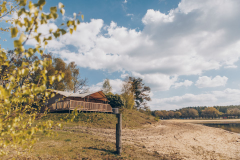 Uitzicht op de Glamfield Lodge premium safaritent bij het meer van Wilsumer Berge, Duitsland, op een zonnige dag.