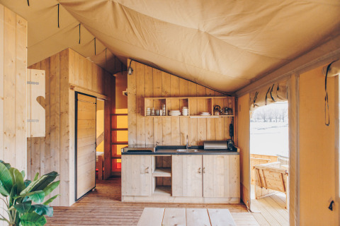 Interieur van Glamfield Lodge Premium safaritent bij Wilsumer Berge in Duitsland met houten keuken.
