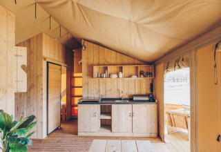 Interieur van Glamfield Lodge Premium safaritent bij Wilsumer Berge in Duitsland met houten keuken.