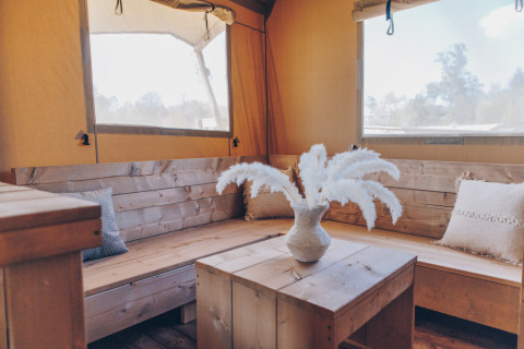 Interieur van Glamfield Lodge Premium safaritent bij Wilsumer Berge, Duitsland, met houten bank en kussens.