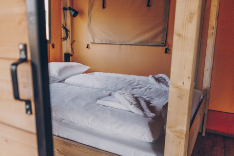 Interieur van een Glamfield Lodge Premium safaritent met een bed bij Wilsumer Berge in Duitsland.