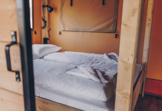 Interieur van een Glamfield Lodge Premium safaritent met een bed bij Wilsumer Berge in Duitsland.