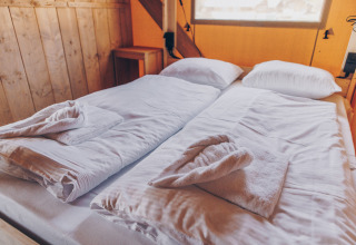 Twee eenpersoonsbedden met witte lakens en handdoeken in een safaritent bij Glamfield Lodge, Wilsumer Berge.