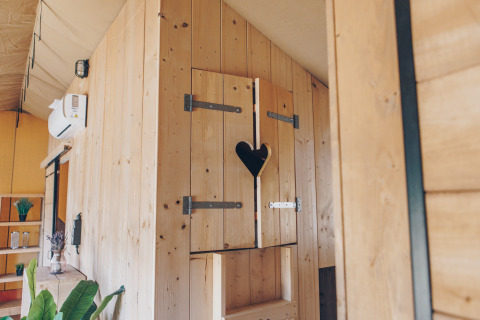 Houten badkamer met hartvormig raampje in Glamfield Lodge Premium safaritent bij Wilsumer Berge, Duitsland.
