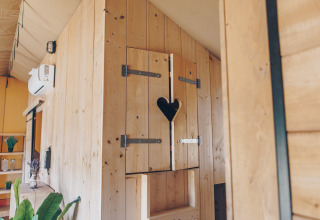 Houten badkamer met hartvormig raampje in Glamfield Lodge Premium safaritent bij Wilsumer Berge, Duitsland.