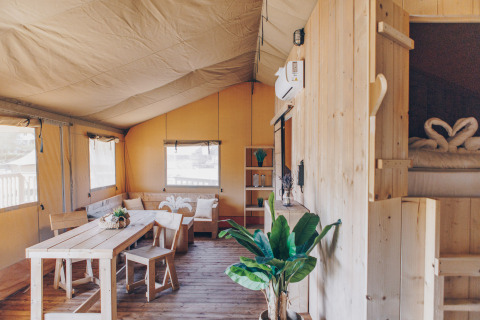 Interieur van de Glamfield Lodge premium safaritent met houten meubels en planten, Wilsumer Berge, Duitsland.