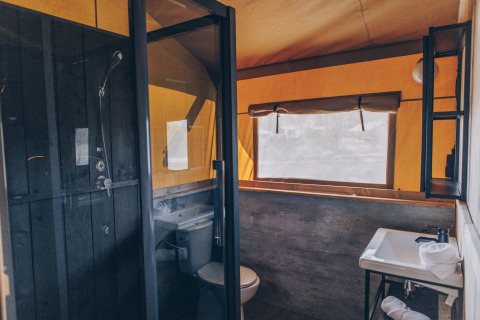 Badkamer in een safaritent van Glamfield Lodge Premium, Wilsumer Berge, Duitsland, met douche en raam.