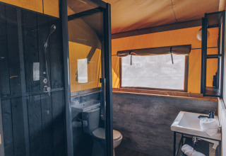 Badkamer in een safaritent van Glamfield Lodge Premium, Wilsumer Berge, Duitsland, met douche en raam.