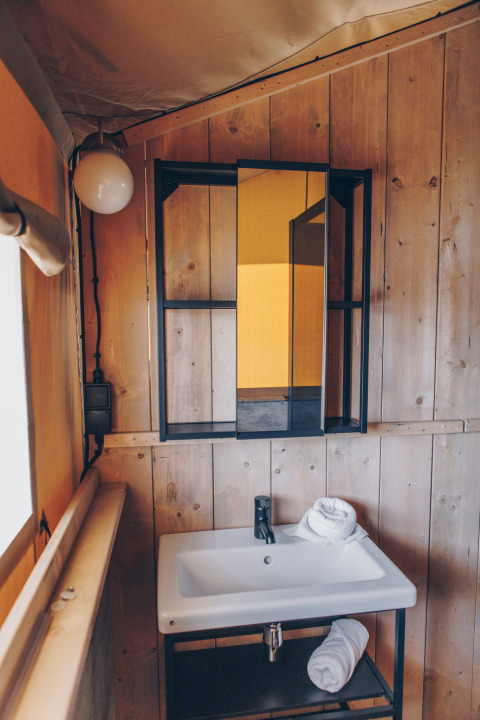 Badkamer in een Glamfield Lodge Premium safaritent bij Wilsumer Berge, Duitsland, met wastafel en houten wanden.