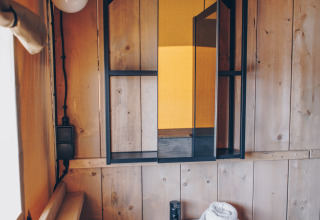 Badkamer in een Glamfield Lodge Premium safaritent bij Wilsumer Berge, Duitsland, met wastafel en houten wanden.