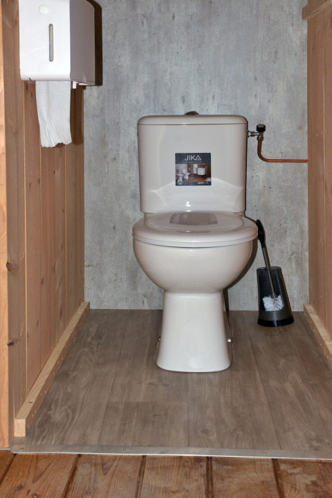 Toilet in een safaritent op Camping de Krabbeplaat in Nederland, met houten vloer en panelen.
