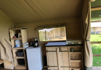Coin cuisine dans une tente safari avec réchaud, frigo et étagères au Camping de Regenboog, République tchèque.