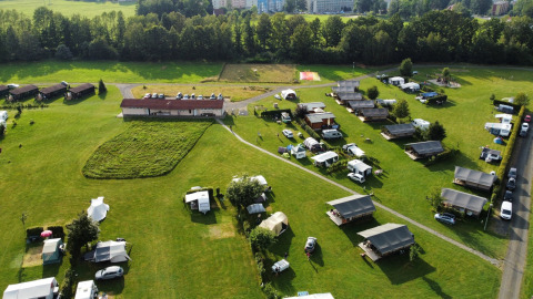 Aerial view of safari tents, caravans, and buildings at Camping de Regenboog in Czech Republic, surrounded by grass.