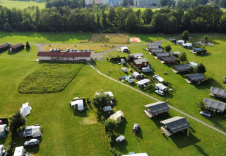 Luftaufnahme von Safari-Zelten, Wohnwagen und Gebäuden auf Camping de Regenboog in Tschechien, umgeben von Grün.
